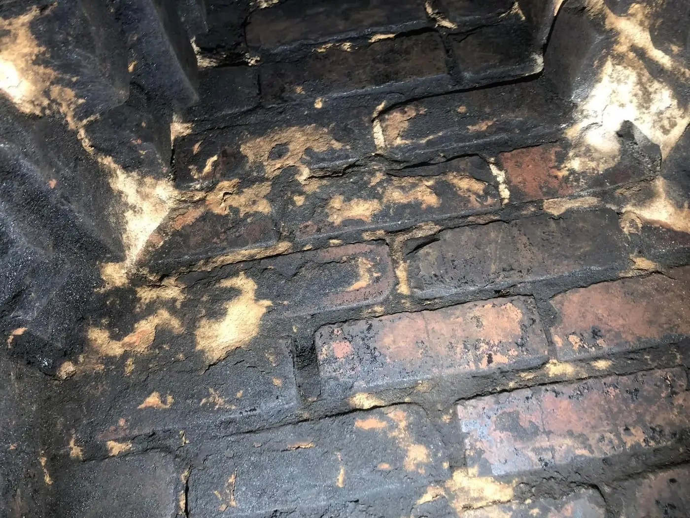 Brick inside a chimney coated in black, shiny creosote.