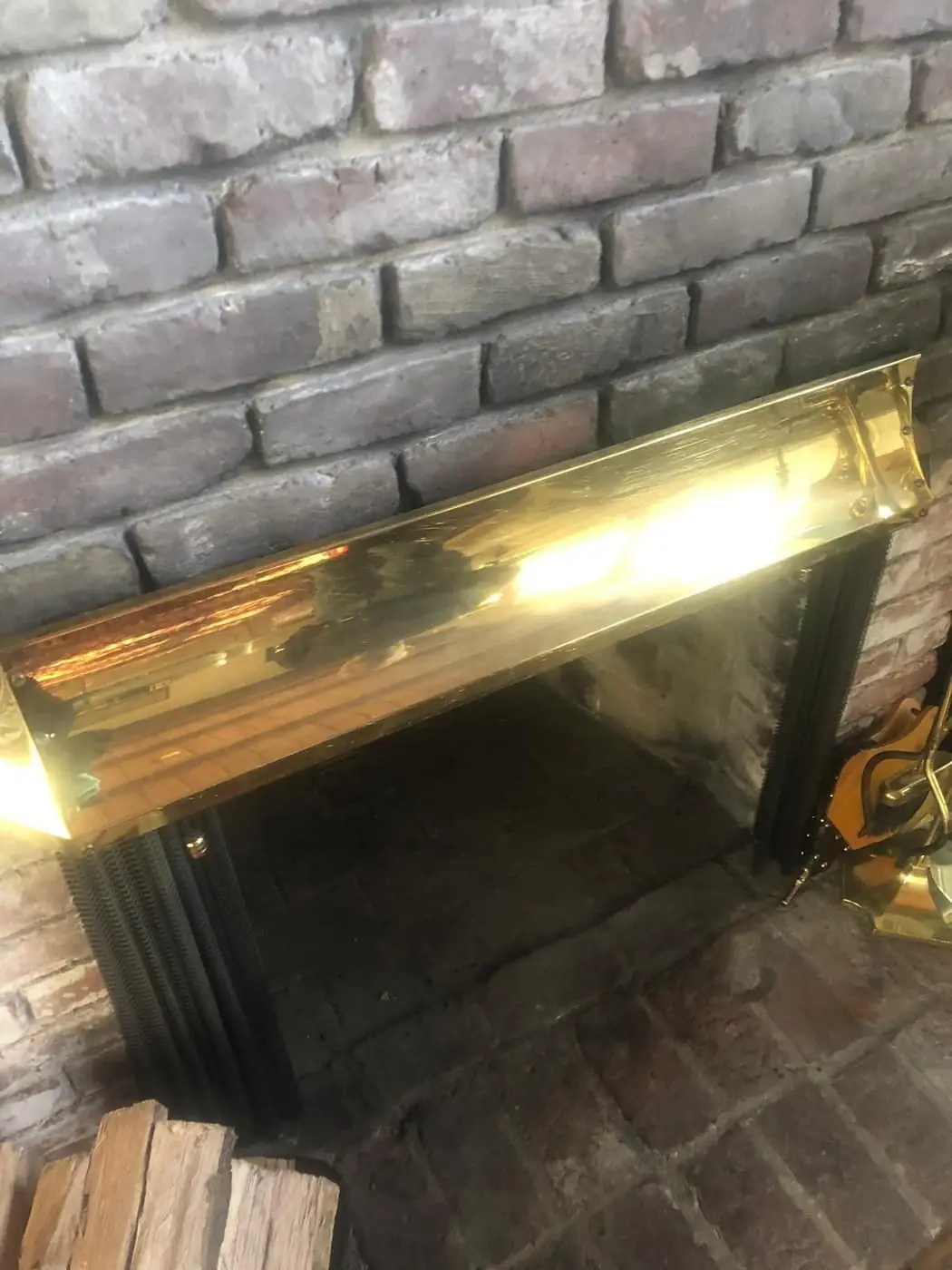 A brick fireplace with a brass-trimmed opening and a black frame.