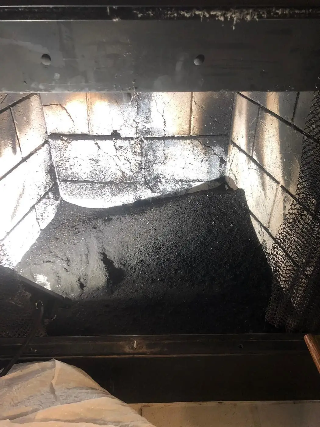 Soot collected on the floor of a metal-framed fireplace, with a drop cloth in front.