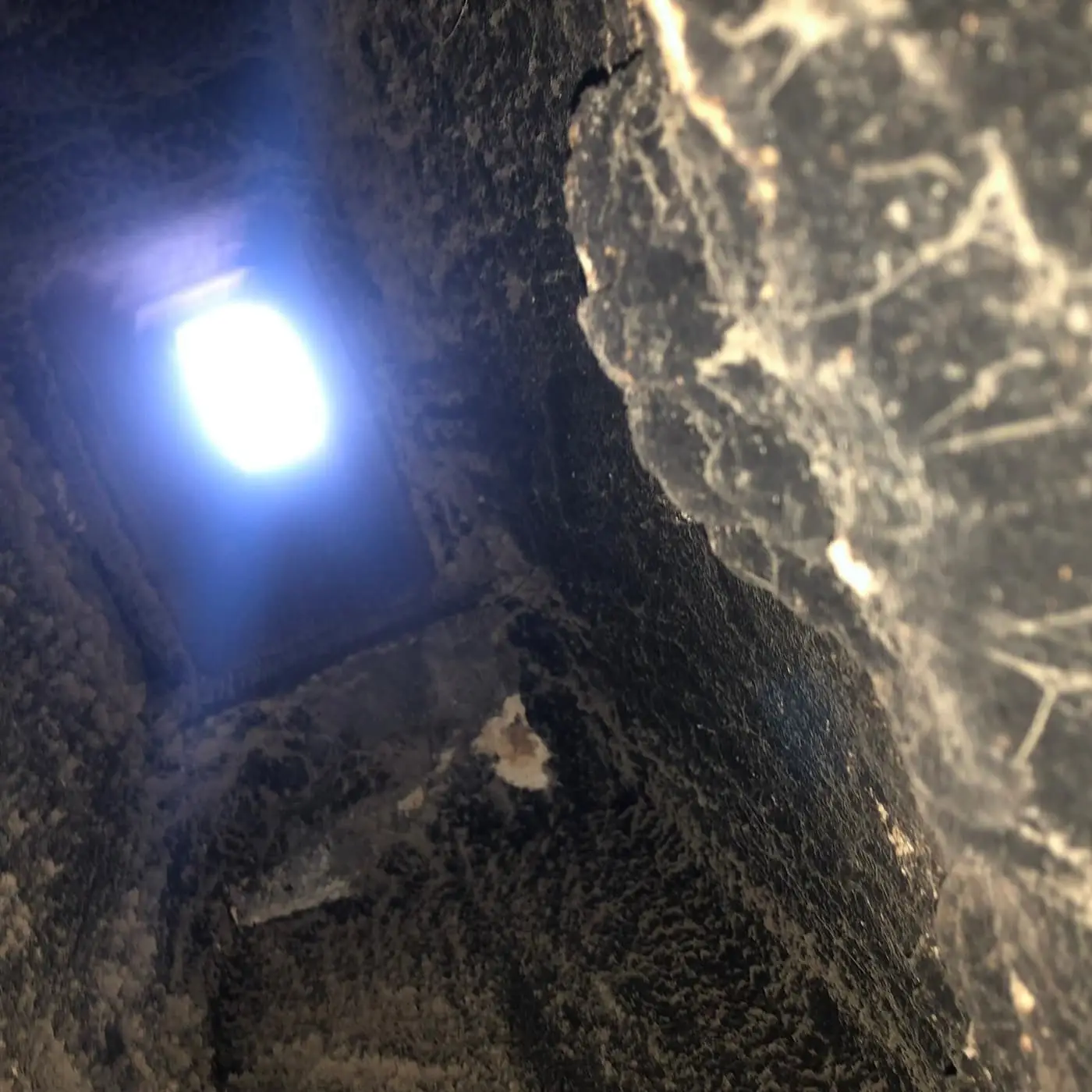 Looking up a flue with heavy black buildup on its walls toward a bright opening at the top.