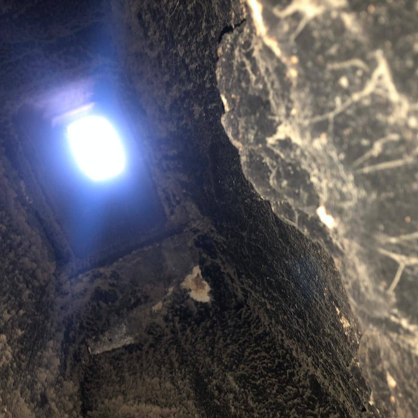 Looking up a flue with heavy black buildup on its walls toward a bright opening at the top.